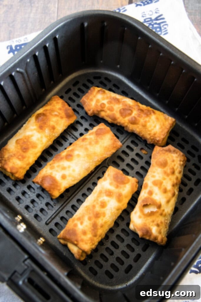 Golden Crispy Air Fryer Egg Rolls 9 Crispy air fried egg rolls resting in the air fryer basket after cooking.