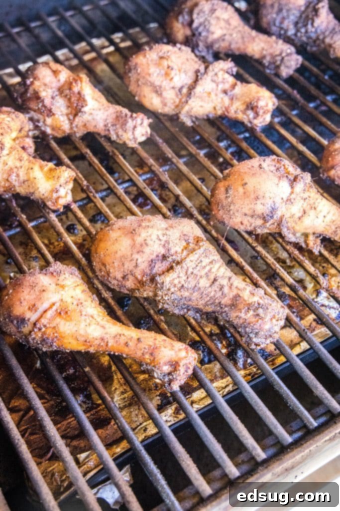Chicken legs actively grilling on a barbecue, with visible char marks and smoke