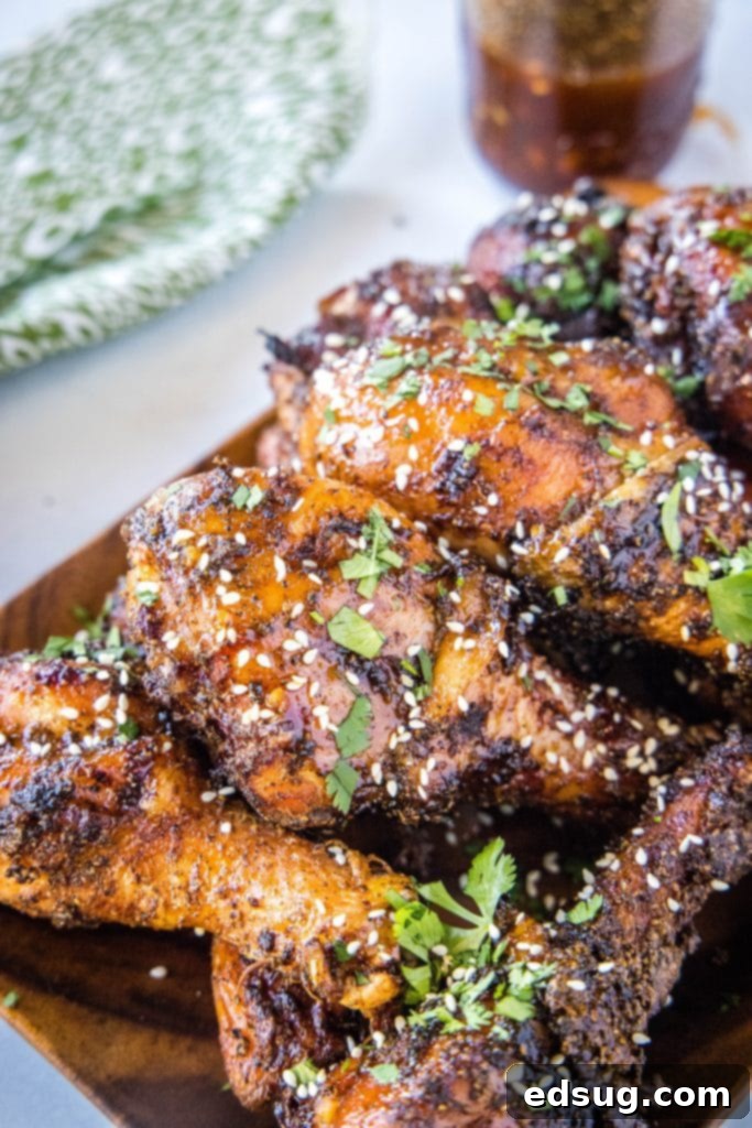 Looking down at a plate of perfectly grilled chicken legs, garnished with sesame seeds and cilantro