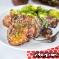 Close-up of a perfectly grilled chicken leg on a plate, garnished with sesame seeds and fresh cilantro