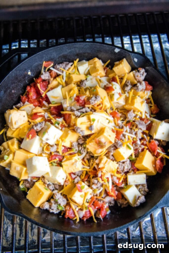 A cast iron skillet filled with mixed queso ingredients being carefully placed into a preheated smoker.