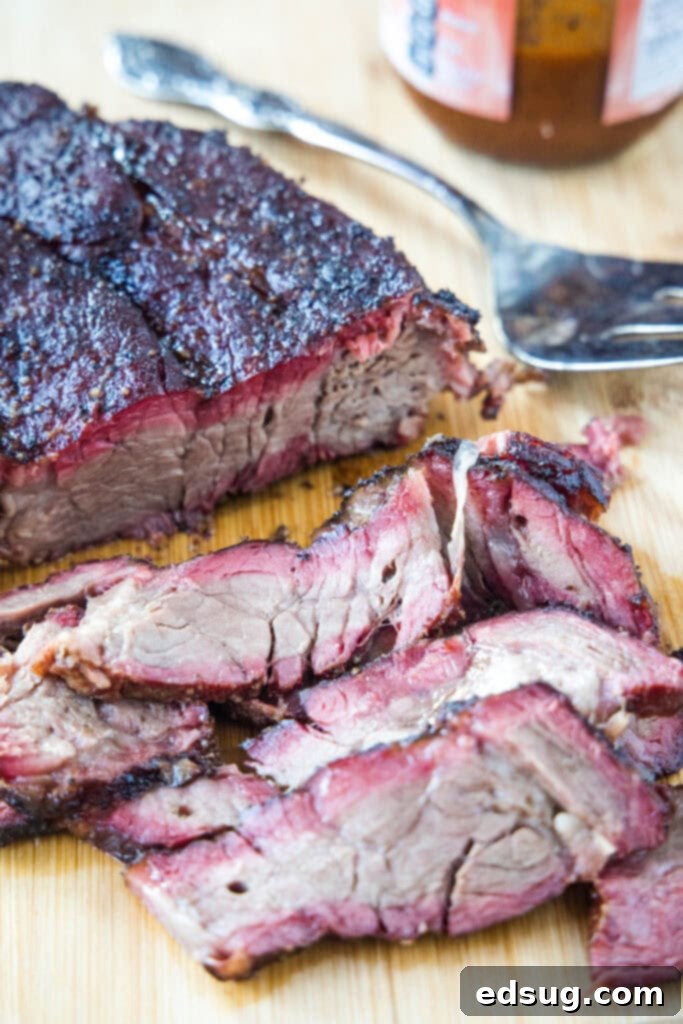 Sliced smoked beef chuck roast on a wooden cutting board, showcasing its tender texture and smoke ring.