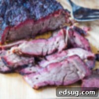 Close up image of tender, sliced chuck roast, showcasing a deep smoke ring and juicy texture.