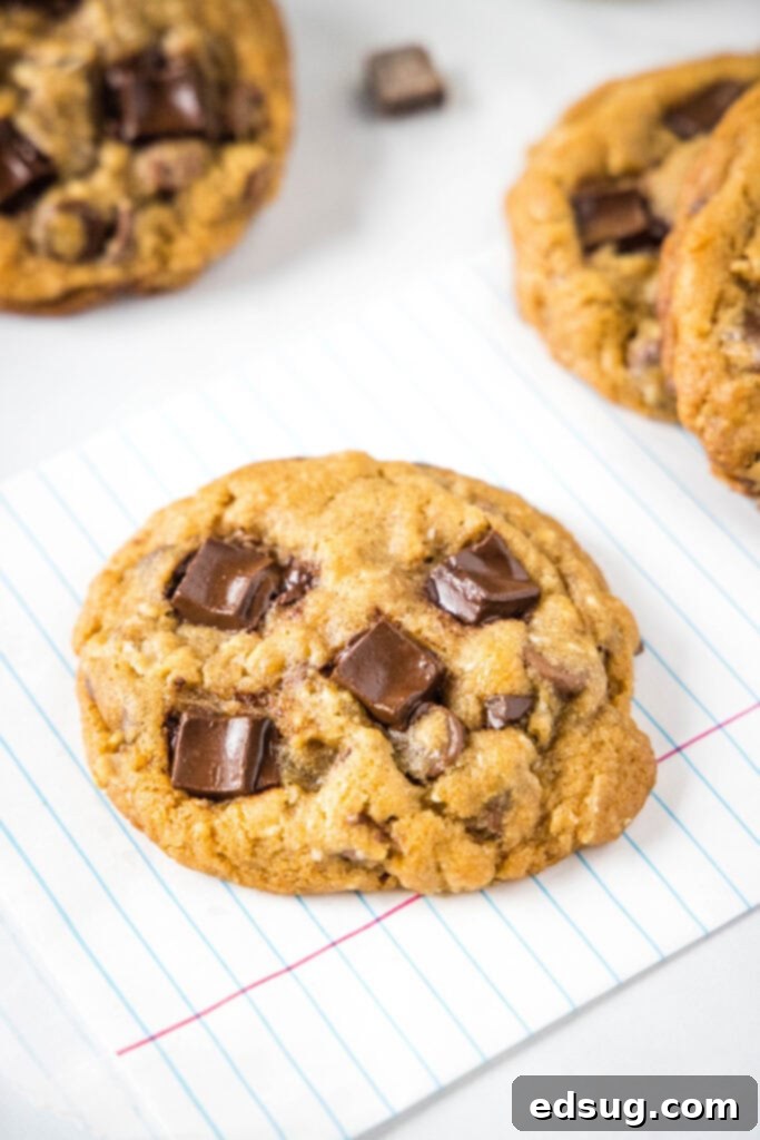 Close-up of golden-brown chocolate chunk cookies on a white surface, highlighting their perfectly baked texture and generous chocolate.