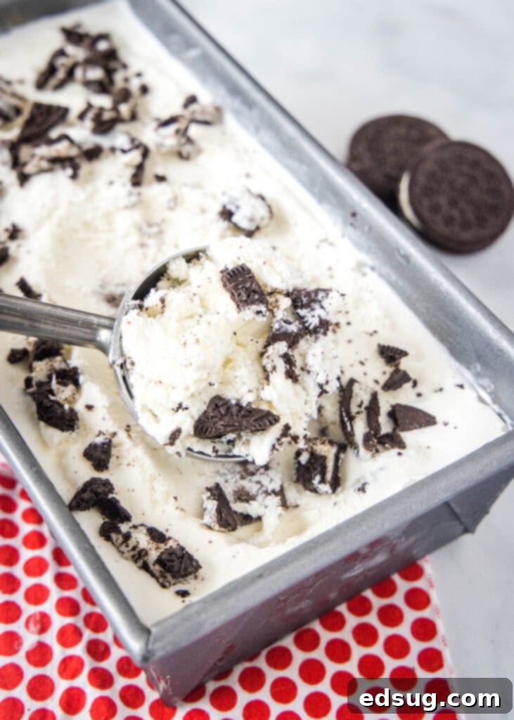Scooping rich homemade Cookies and Cream Ice Cream from a pan, revealing generous Oreo chunks.