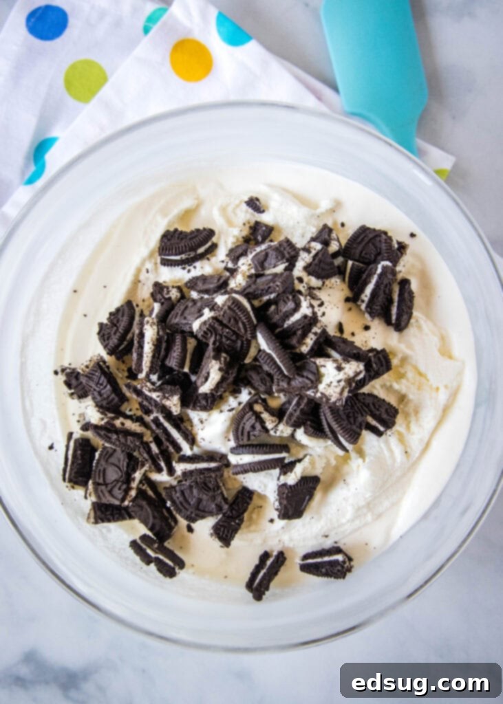 Mixing crushed Oreo cookie pieces into freshly churned ice cream.
