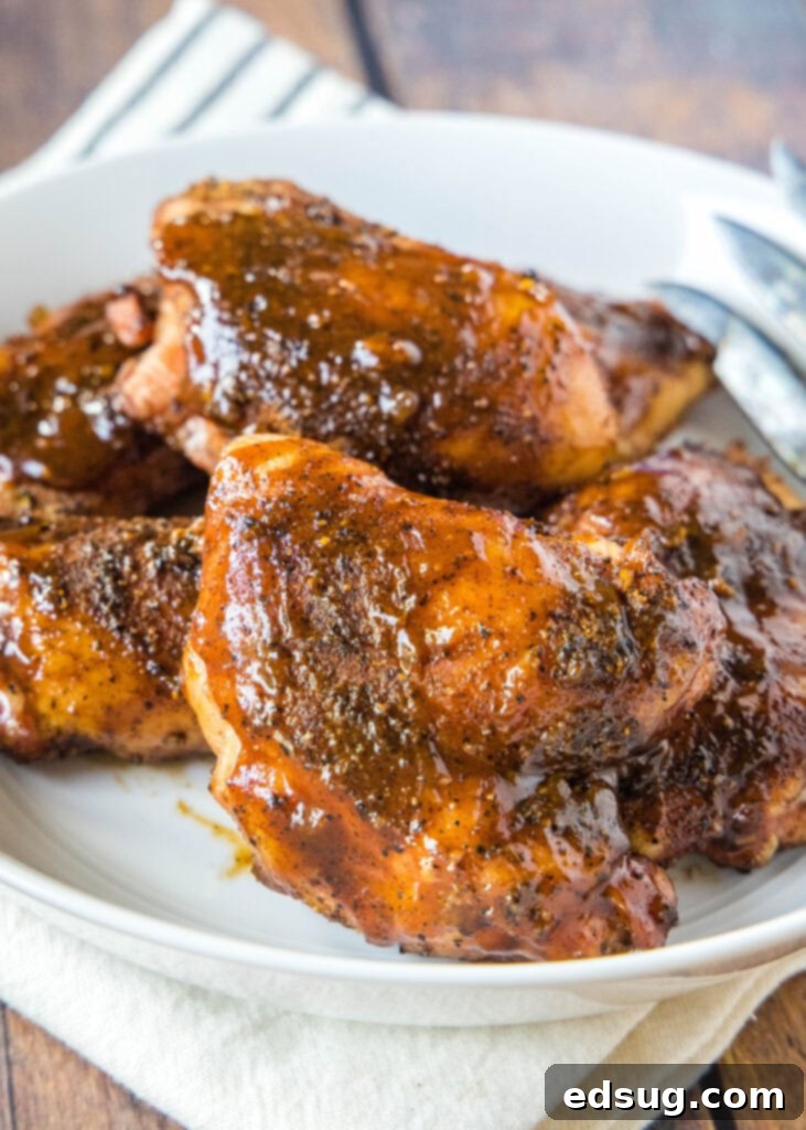 a white platter with smoked chicken thighs brushed in sauce
