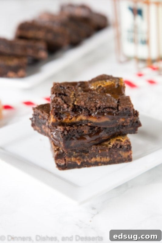 close up of a single chocolate caramel brownie with a bite taken out, revealing the layers