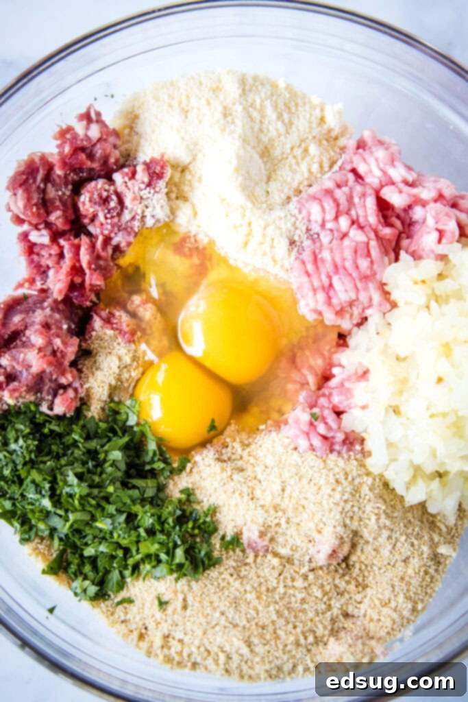 A large mixing bowl filled with all the raw ingredients for Instant Pot Meatballs, including ground beef, pork, breadcrumbs, eggs, grated cheese, and fresh herbs, ready to be combined.