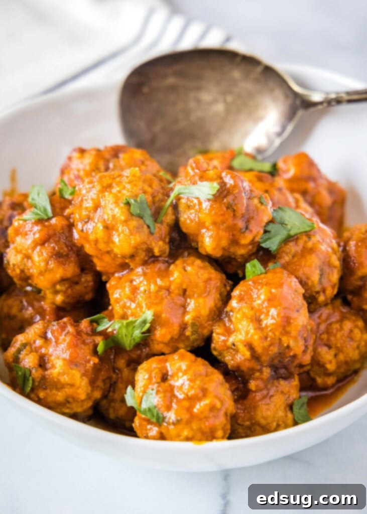 A large serving bowl filled with piping hot Instant Pot Meatballs swimming in marinara sauce, with a serving spoon resting inside, ready for family dinner.