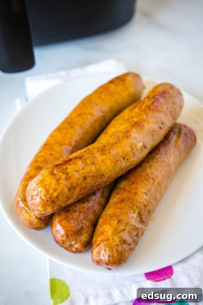 A single perfectly cooked air fryer sausage resting on a clean white plate, ready for serving or garnishing.