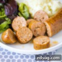 sliced air fryer sausage on a white plate with a side salad, showing a quick and delicious meal