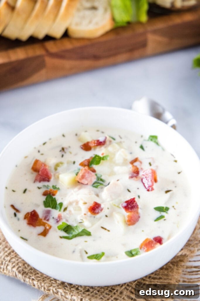 Ultimate Creamy Clam Chowder 5 Looking down into a pristine white bowl filled with creamy clam chowder, highlighting its smooth texture and hearty ingredients.