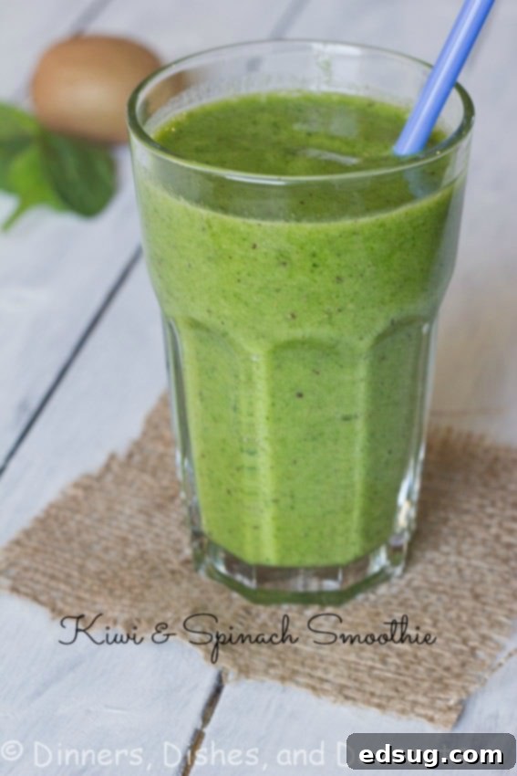 Close-up of a vibrant green kiwi spinach smoothie in a glass, garnished with a kiwi slice.