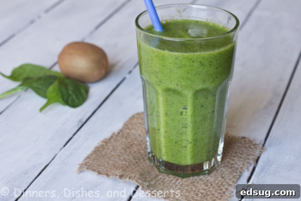 kiwi and spinach smoothie in a clear cup with a straw.