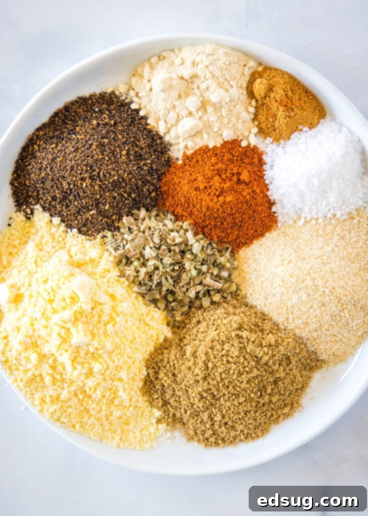 Ingredients for homemade taco seasoning laid out on a plate, including chili powder, cumin, oregano, onion powder, garlic powder, paprika, salt, cayenne pepper, and cornmeal, ready to be mixed.