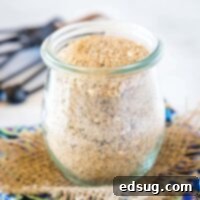 A glass jar filled with homemade taco seasoning with vibrant spices visible.