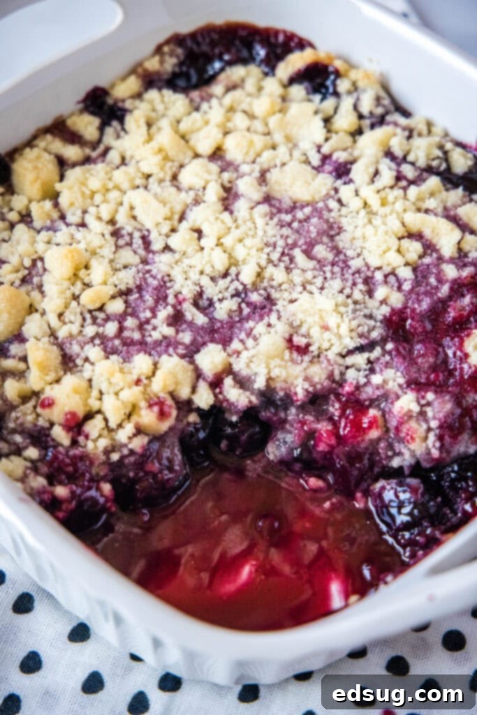 Cherry Cobbler 5 A baked cherry cobbler in a casserole dish with a scoop missing, revealing the juicy cherry filling.