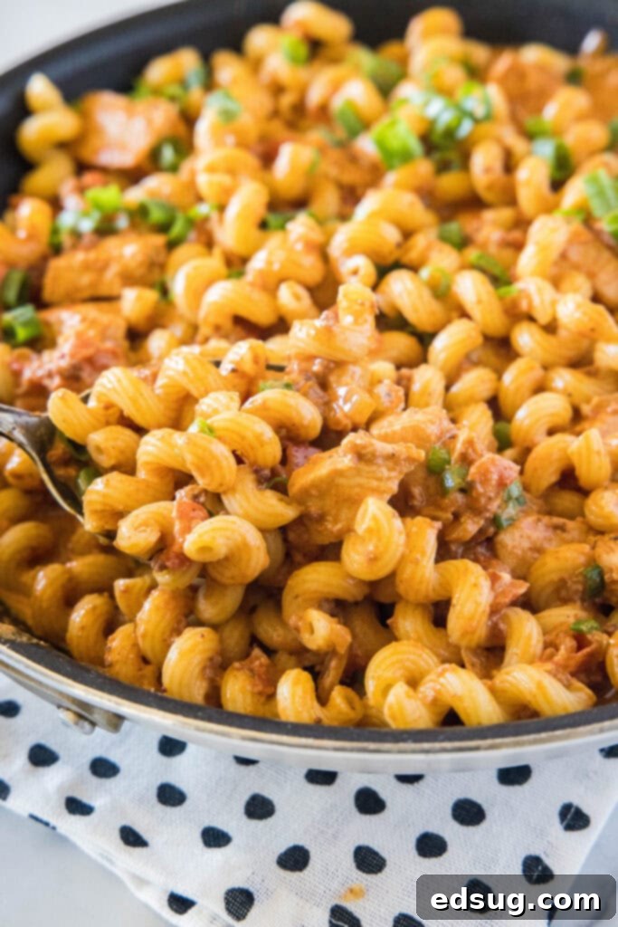 Smoky Chicken Chorizo Pasta 6 taking a scoop of pasta out of skillet