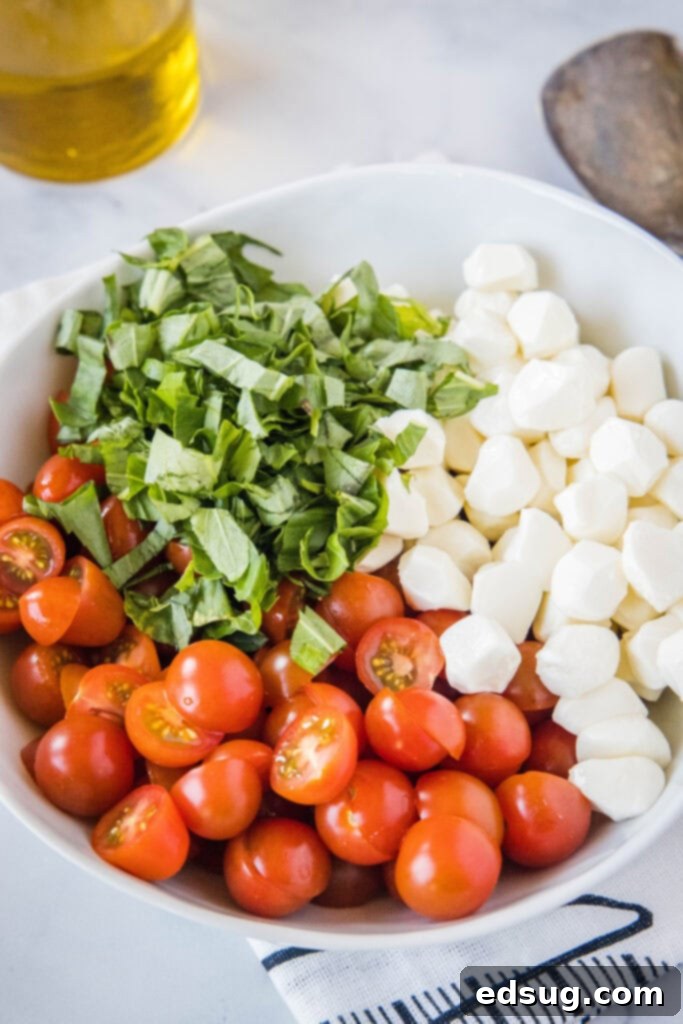 Close-up of tomatoes, basil, and mozzarella pearls freshly mixed in a bowl before dressing.