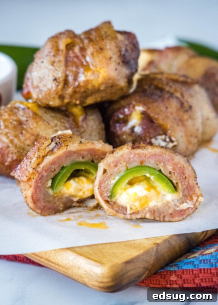 Smoked Armadillo Eggs cut in half, revealing cheesy jalapeno filling and perfectly cooked sausage and bacon on a cutting board