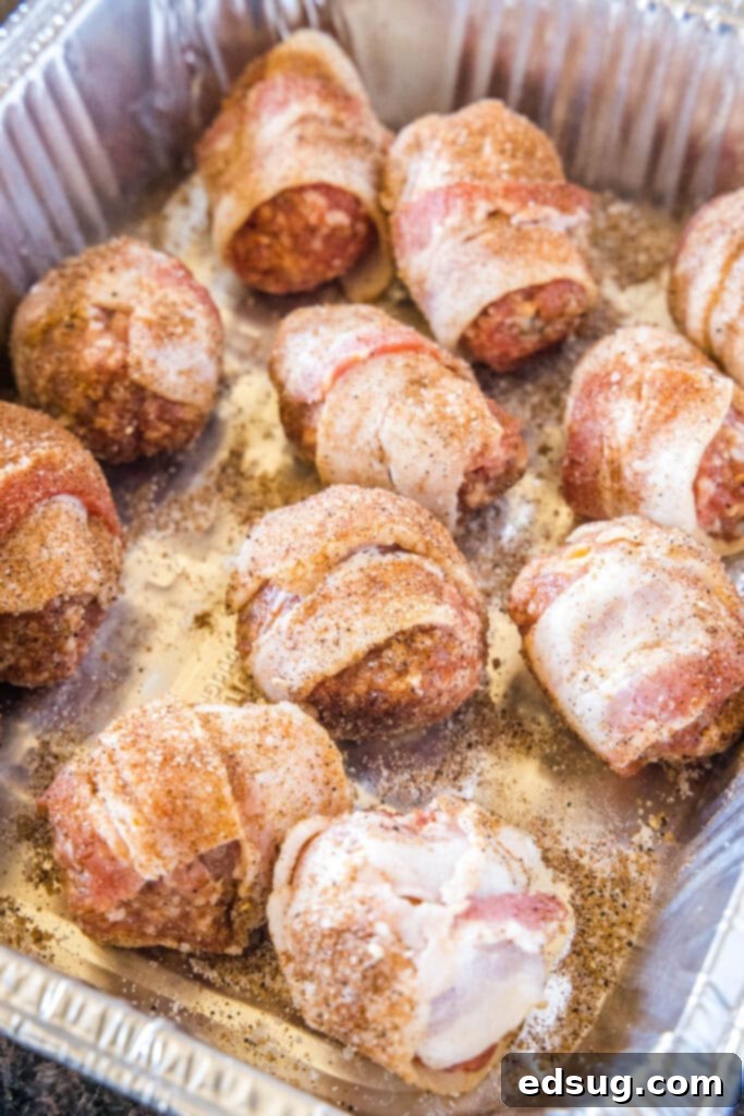 Armadillo eggs seasoned with dry rub, arranged on a smoking rack, ready to be placed in the smoker