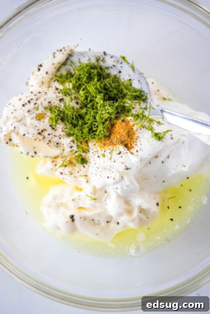 A bowl of creamy dill pickle pasta salad dressing being mixed.