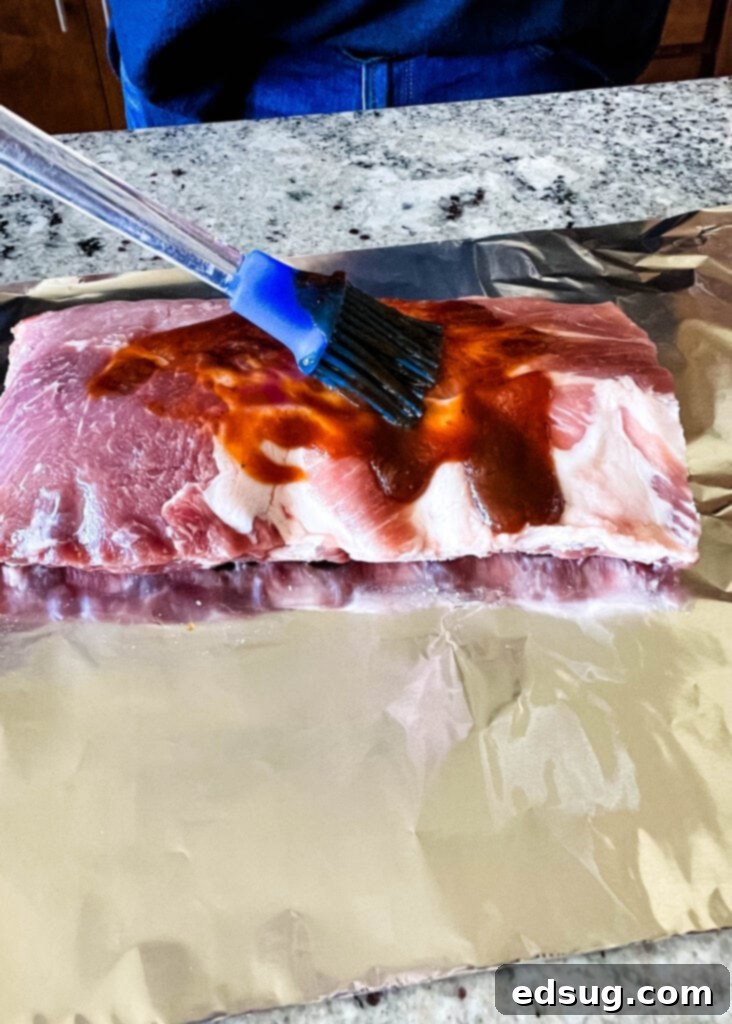 brushing sauce on raw baby back ribs
