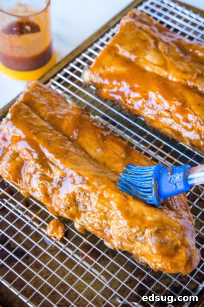 brushing sauce on ribs on a baking tray
