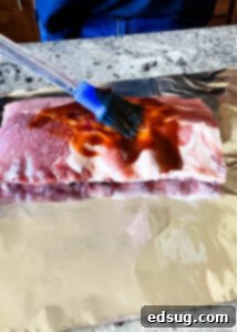 brushing sauce on raw baby back ribs