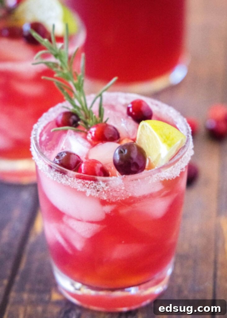 Close-up of a festive Mistletoe Margarita garnished with fresh cranberries and a sprig of rosemary, ready to be enjoyed.