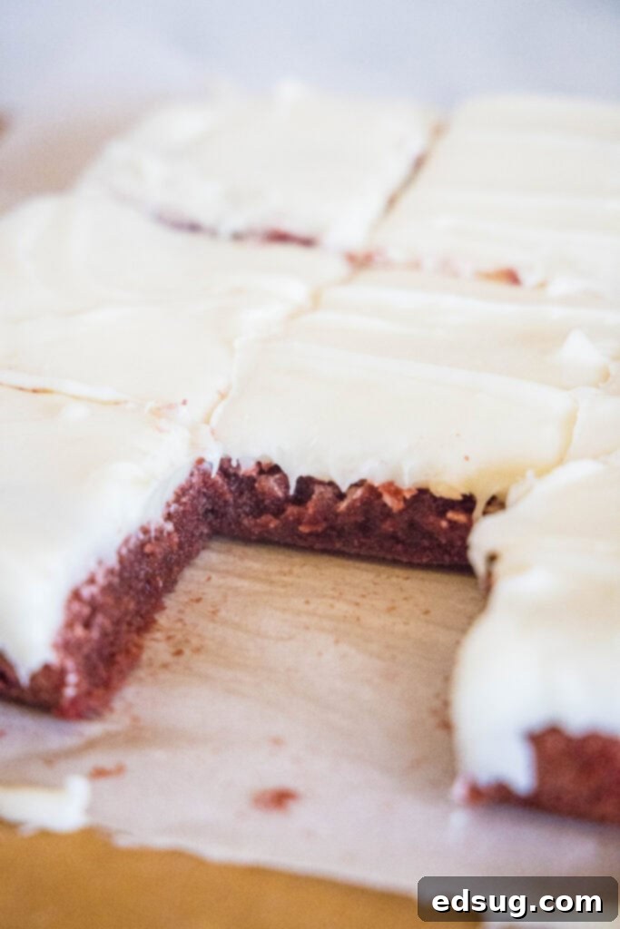Perfectly sliced red velvet brownies on a wooden cutting board, showcasing their vibrant red color and fudgy texture.
