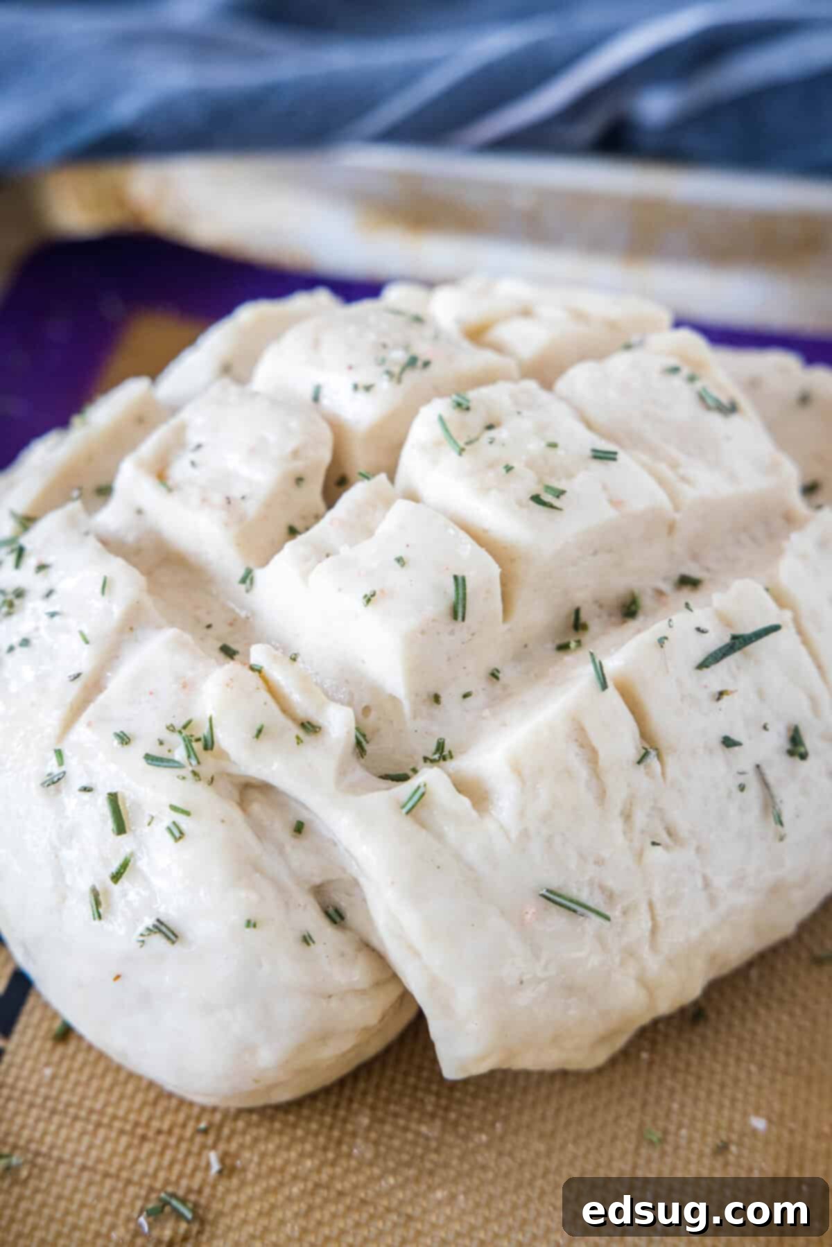 Amish bread dough, brushed with egg wash and sprinkled with rosemary and coarse salt, ready to be baked in the oven.