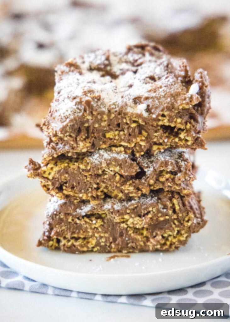 Stack of fudgy Puppy Chow Bars on a white plate, dusted with powdered sugar.