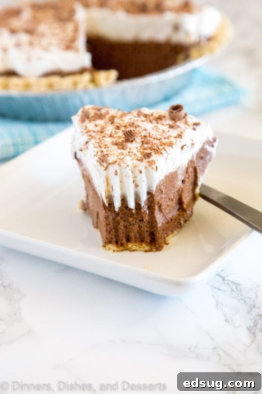 Close-up of a slice of French Silk Pie, showing the layers of chocolate mousse, whipped cream, and chocolate shavings.