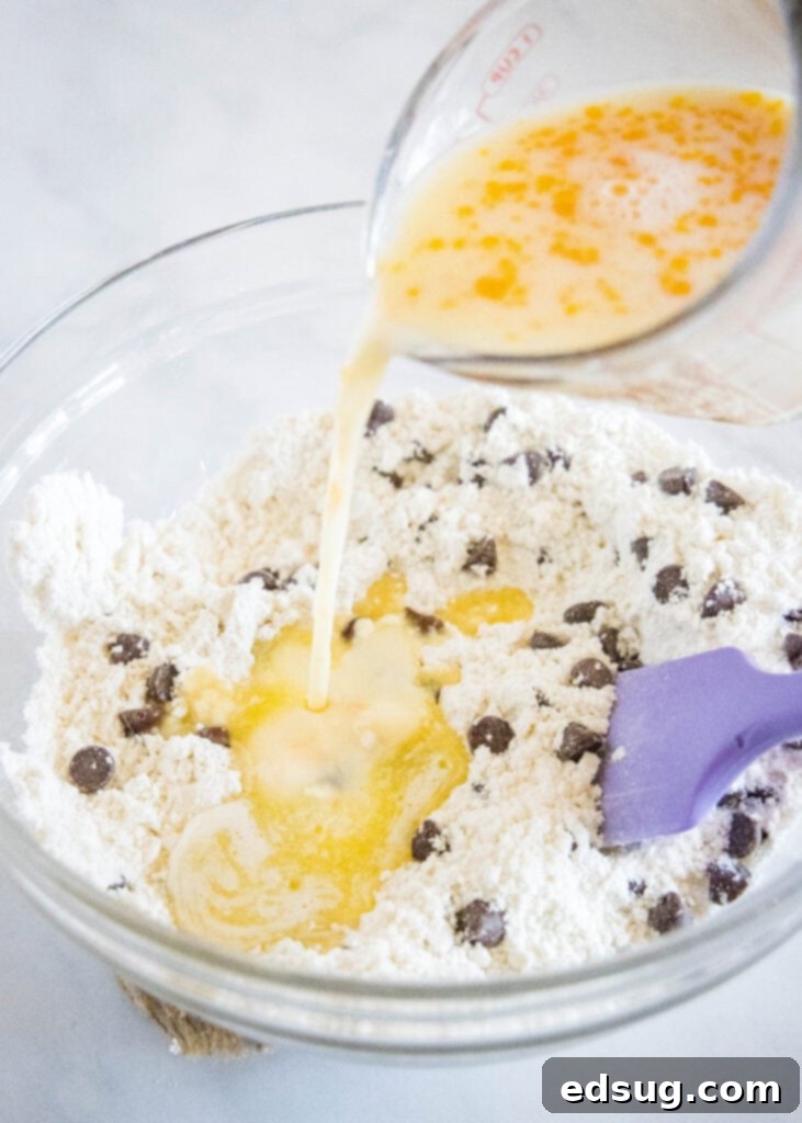 Hands pouring milk and a whisked egg into a mixing bowl containing Bisquick mix and sugar, preparing the muffin batter.