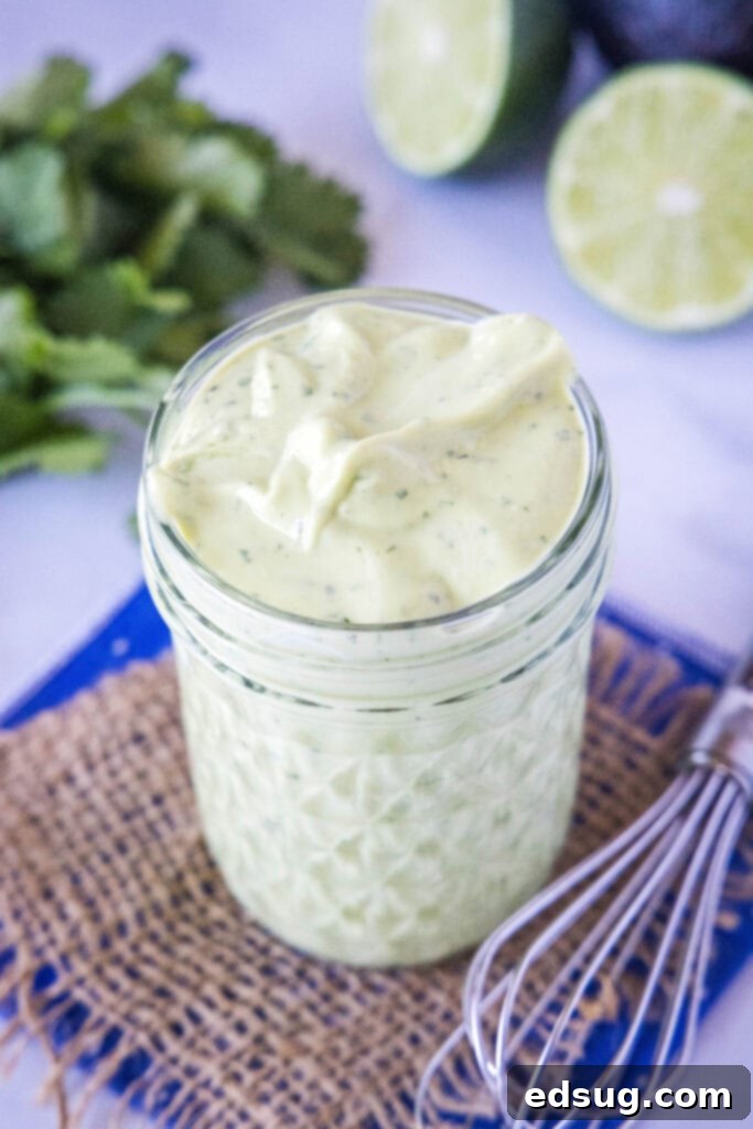 A close-up, top-down view of vibrant green avocado dressing beautifully presented in a clear mason jar, showcasing its smooth, creamy texture and readiness to be served.