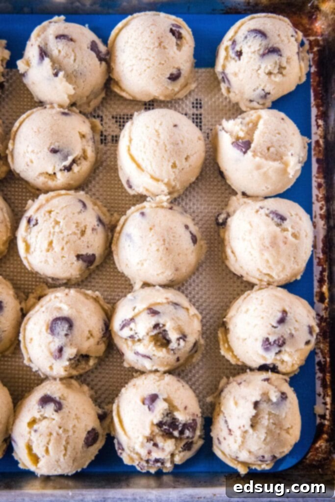 Balls of perfectly scooped cream cheese chocolate chip cookie dough on a baking sheet, ready for chilling.