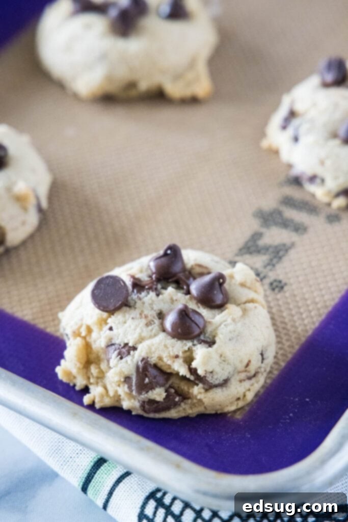 Close up of a few freshly baked cream cheese chocolate chip cookies on a baking sheet, just out of the oven.