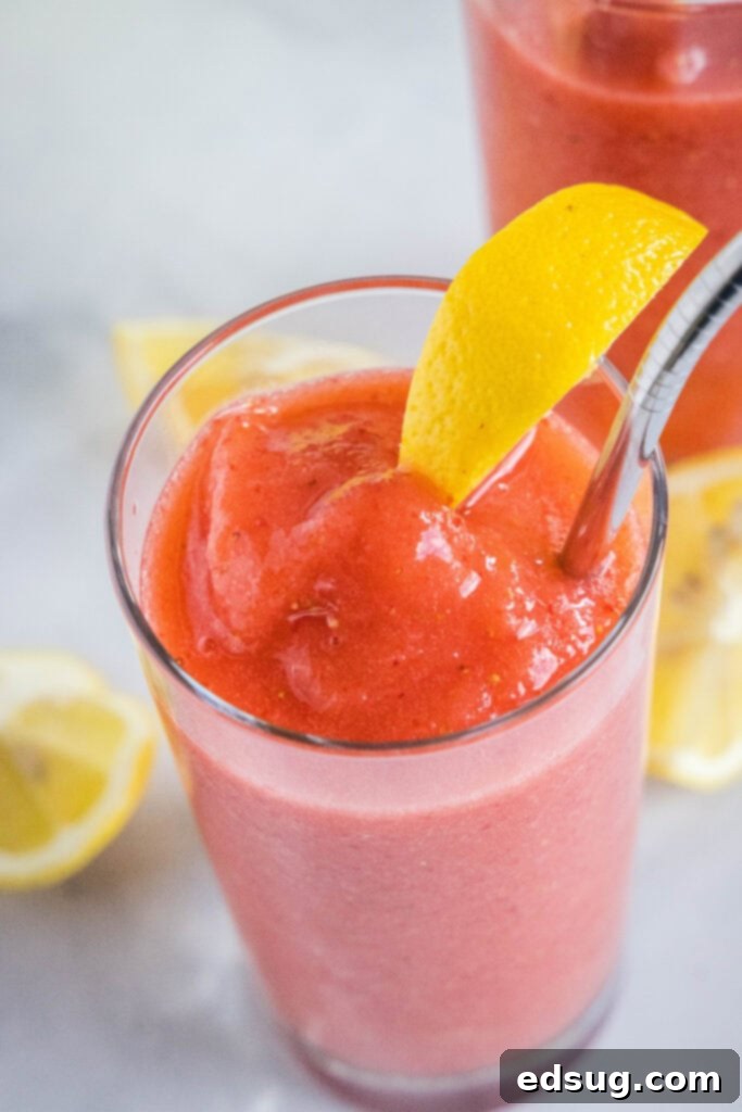 Close-up overhead shot of a glass of frozen strawberry lemonade, garnished with a vibrant red strawberry and a bright yellow lemon slice.