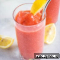 A frosty glass of frozen strawberry lemonade, garnished with a lemon slice, ready to be enjoyed.