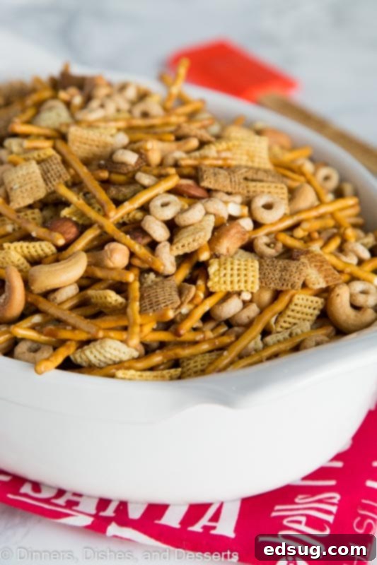 A close-up shot of crispy Chex Party Mix piled high on a plate, showcasing the various textures of cereals, pretzels, and nuts, coated in a savory glaze. SEO keywords: Homemade Chex Mix, Savory Snack, Traditional Recipe.