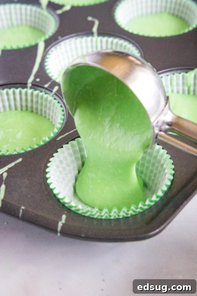 Watermelon Cupcakes 4 Cupcake batter, dyed green, being carefully spooned into muffin liners in a baking tin.