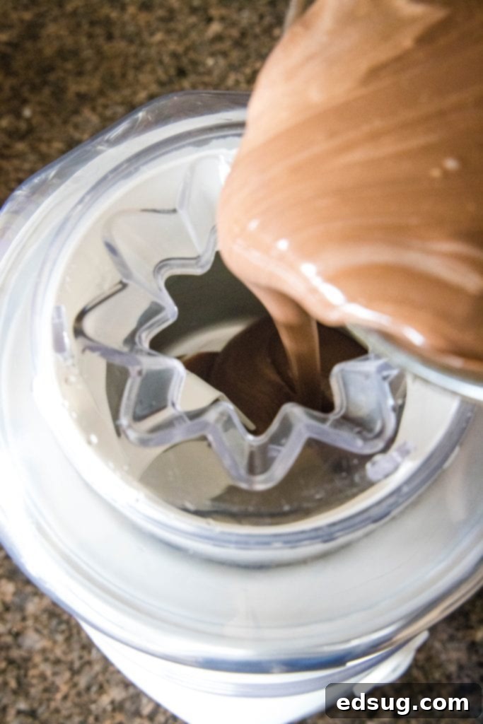 Pouring the chilled chocolate ice cream custard mixture into an ice cream maker.