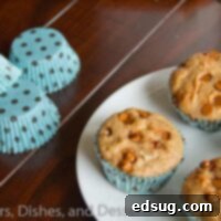 Four perfectly golden whole wheat cinnamon muffins cooling on a wire rack, sprinkled with extra cinnamon chips for a tempting finish.