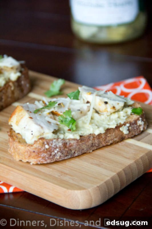 open faced chicken sandwich with artichoke pesto on a board