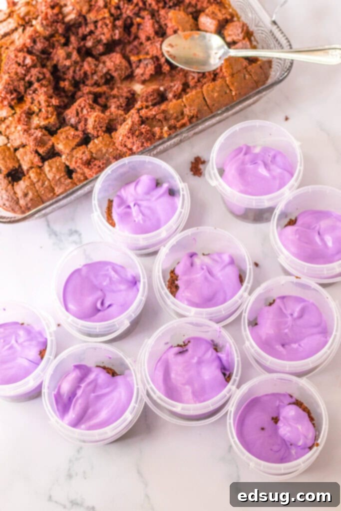 Hands layering cake and pudding into clear cups for Halloween pudding cups