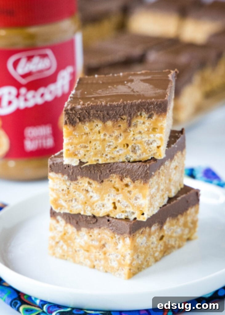stacked krispie treats on a white plate with jar of biscoff spread