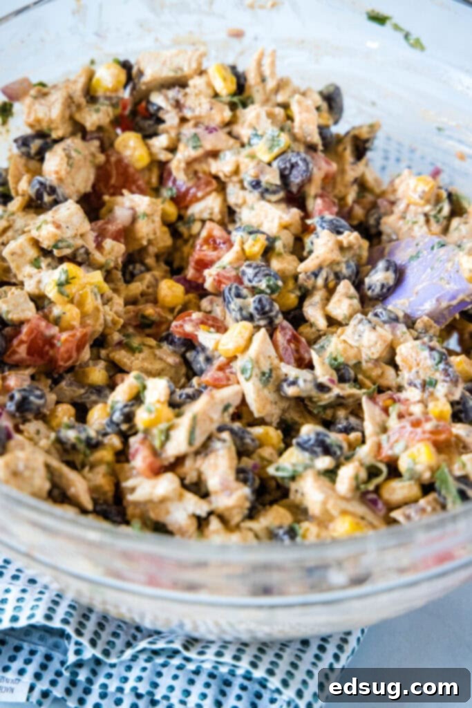A spatula stirring chicken salad in a bowl