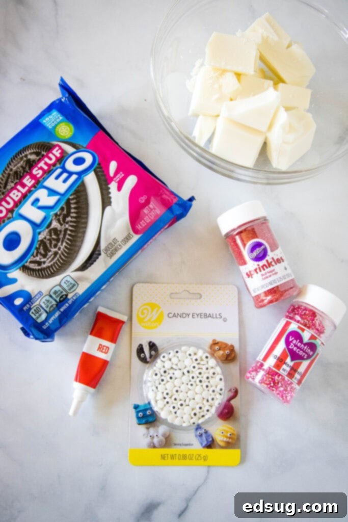 A beautiful flat lay of all the essential ingredients needed for Love Bug Oreo Cookies, including classic Oreo cookies, white chocolate melting wafers, a bottle of red oil-based food coloring, a jar of whimsical candy eyes, and festive Valentine's Day sprinkles.